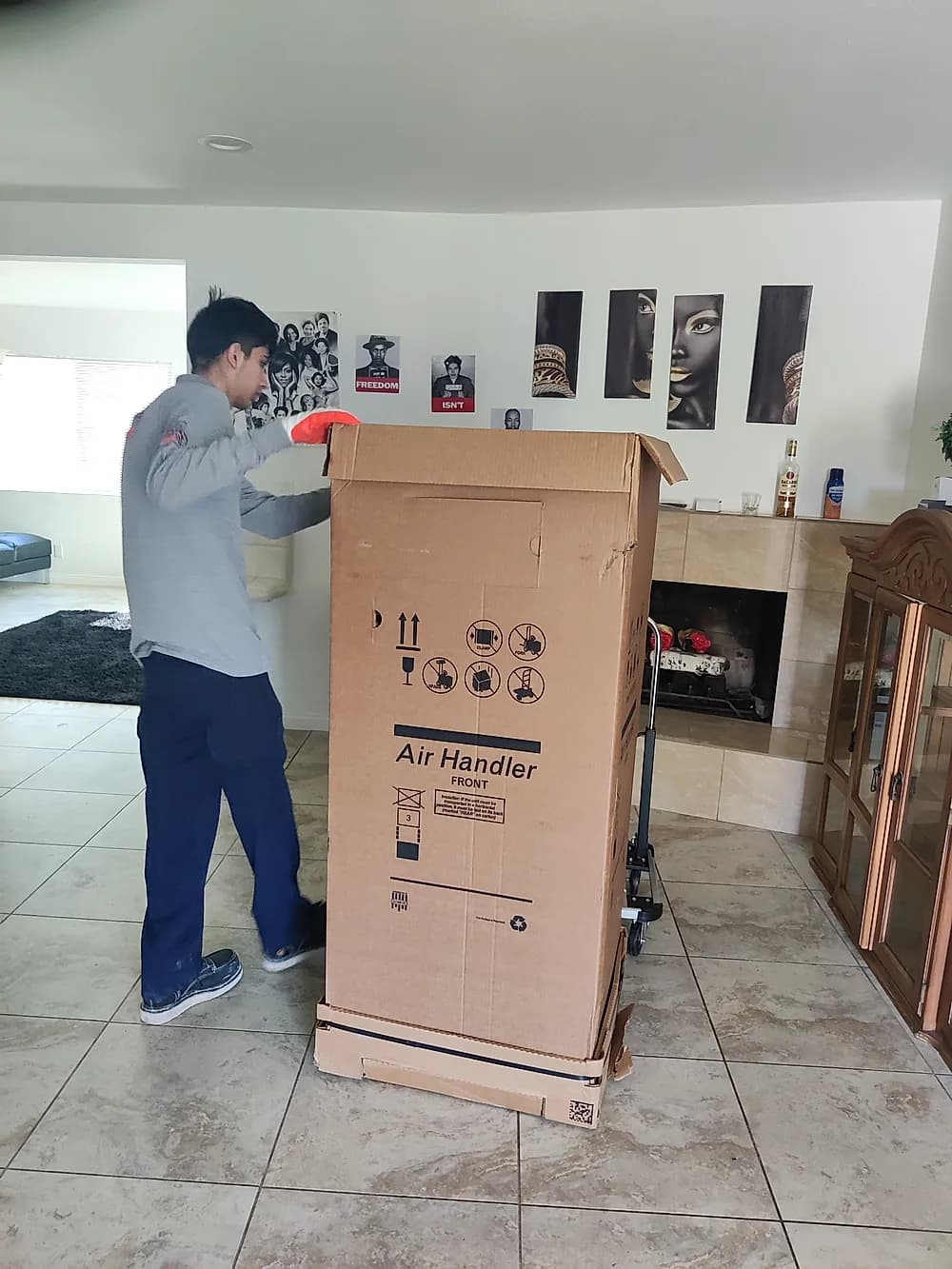 Technician moving a new air handler unit into a customer's home on a hand truck