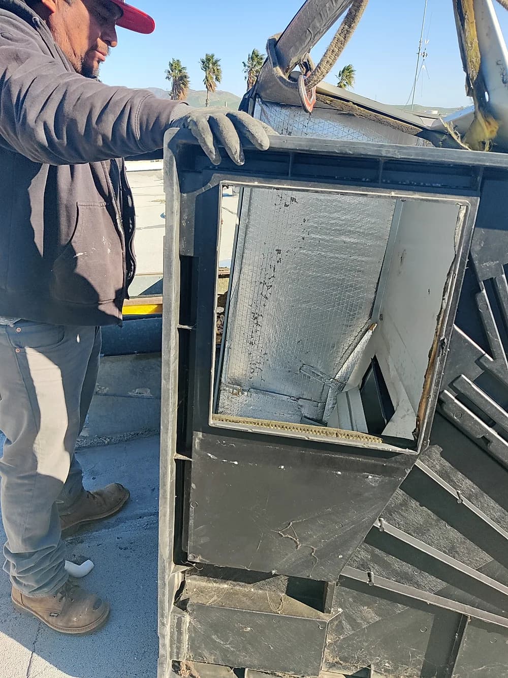 Trust technician servicing a commercial rooftop condensing unit on a lift platform